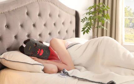 A woman is sleeping on the bed and using red light therapy.